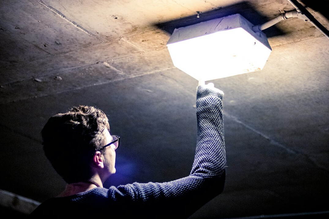 Lighting technician adjusting a spotlight on a ladder in a television studio