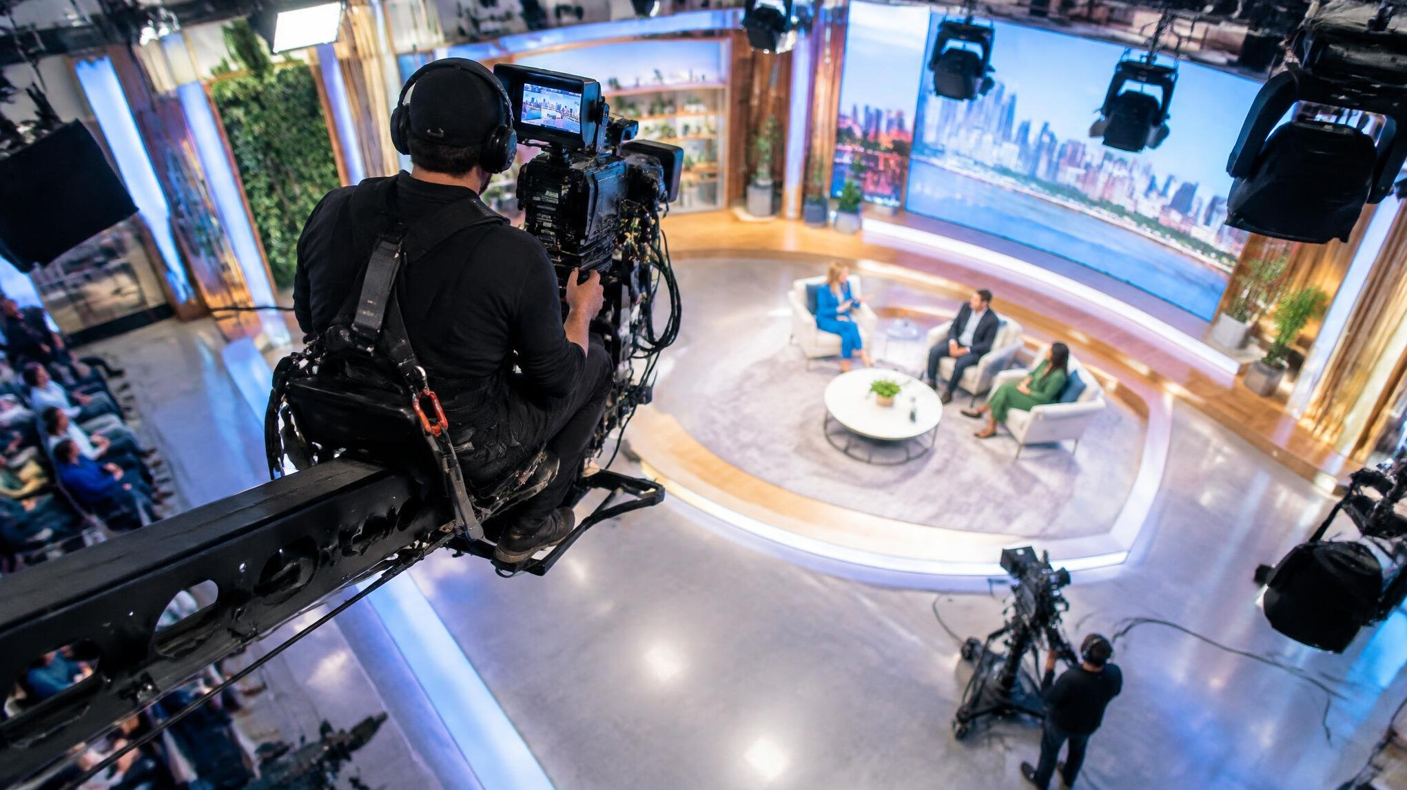 Camera operator using a jib crane to film a live studio set